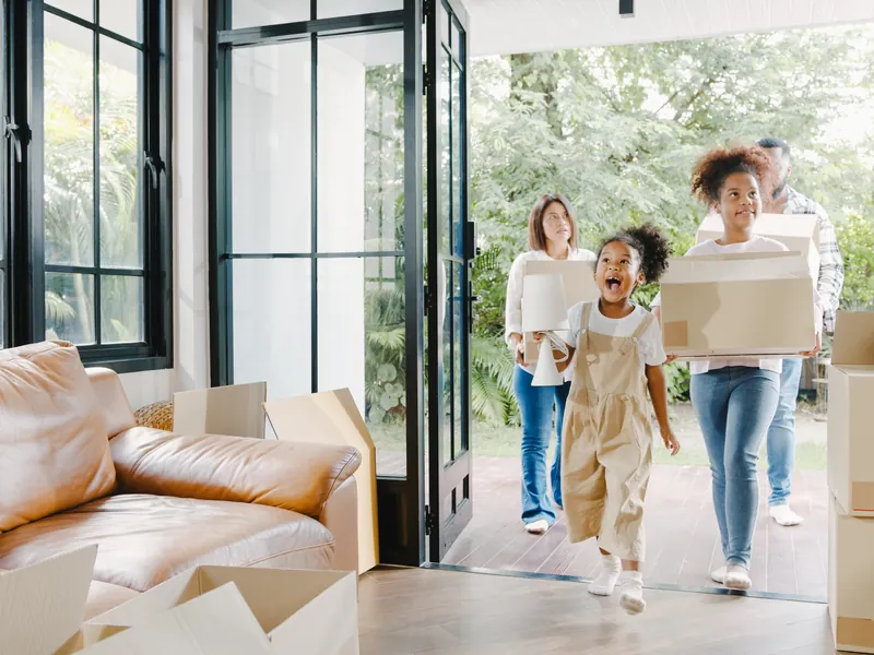 A family carrying boxes into their bright new London home